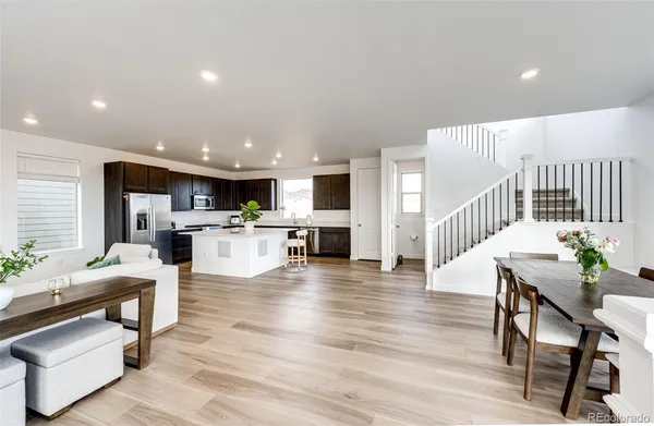 a living room with furniture and kitchen view with wooden floor