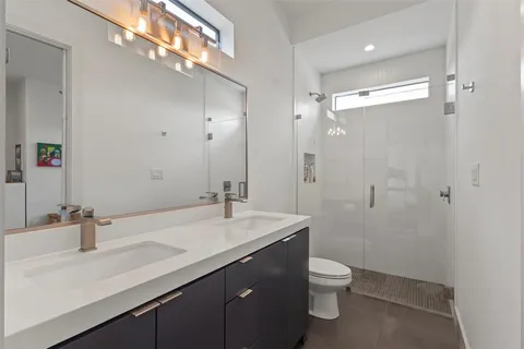 a bathroom with a granite countertop sink a toilet and a large mirror