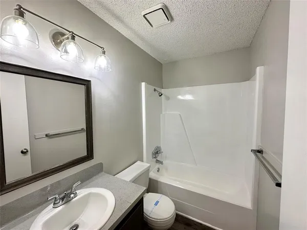 a bathroom with a granite countertop sink toilet a mirror a vanity and bathtub