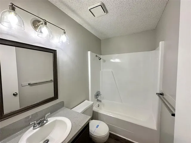 a bathroom with a granite countertop sink toilet a mirror a vanity and bathtub