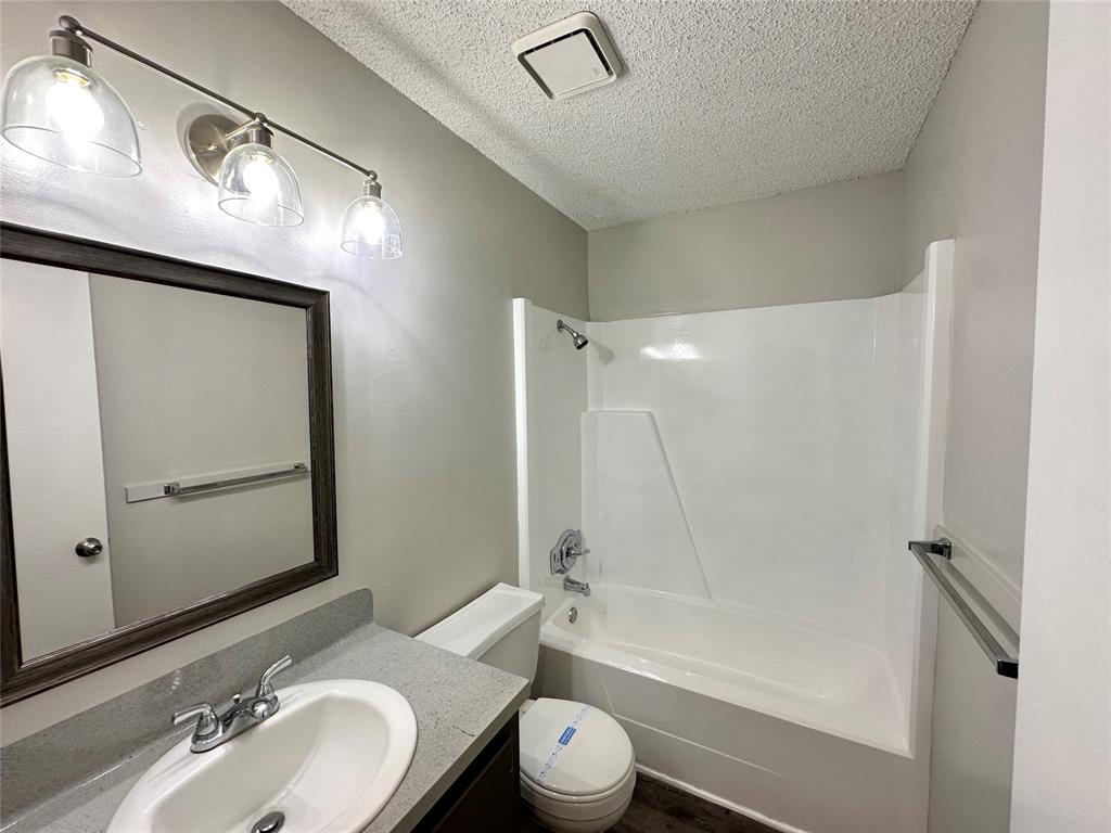 2006 Jane Street, Unit H Longview, TX 75601 - Photo 7 of 12 a bathroom with a granite countertop sink toilet a mirror a vanity and bathtub