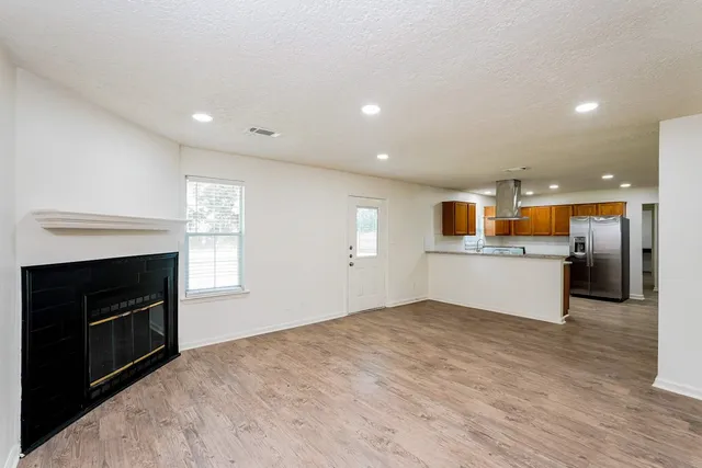 a view of kitchen and empty room with wooden floor