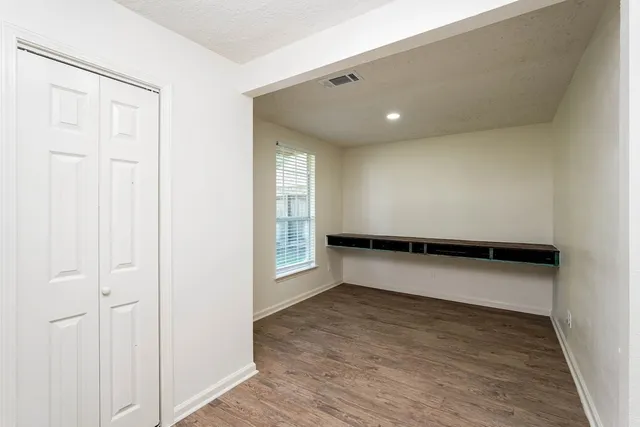 an empty room with windows and fan