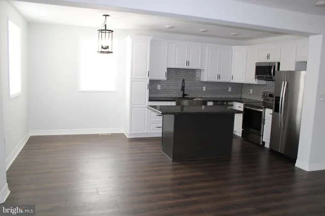 a kitchen with stainless steel appliances granite countertop a stove top oven a sink and a refrigerator