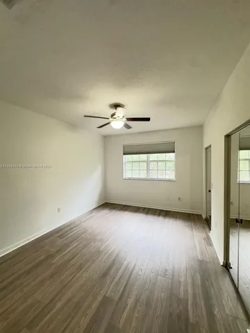an empty room with wooden floor chandelier and windows