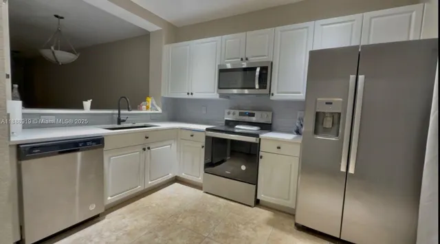 a kitchen with white cabinets and stainless steel appliances