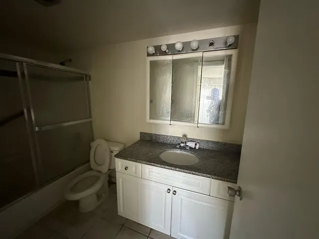 a bathroom with a granite countertop toilet and a sink