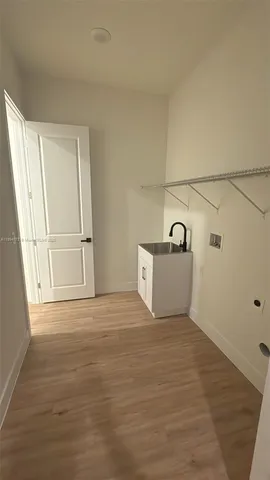 a view of a room that has a sink and wooden floor