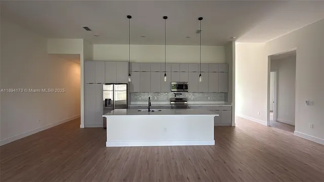 a large kitchen with stainless steel appliances a large counter top a stove and a wooden floors