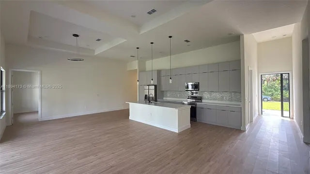 a kitchen with stainless steel appliances kitchen island wooden floors and white walls