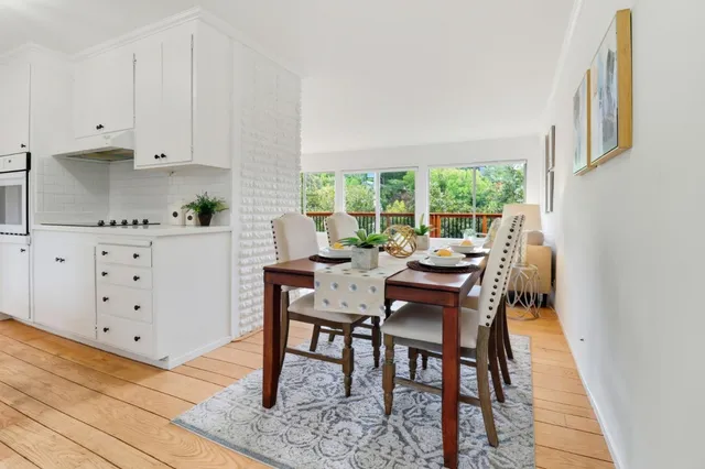 a kitchen with granite countertop a table chairs stove and white cabinets