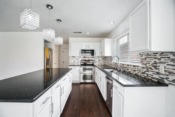 a kitchen with granite countertop a sink stainless steel appliances and cabinets