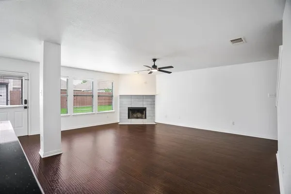 an empty room with wooden floor fireplace and windows