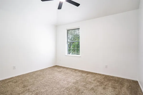 an empty room with a window and a ceiling fan