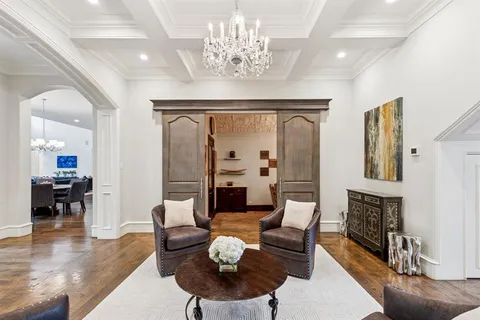 a living room with couches a fireplace and a dining table with wooden floor