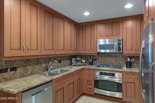 a kitchen with stainless steel appliances granite countertop wooden cabinets a sink and dishwasher
