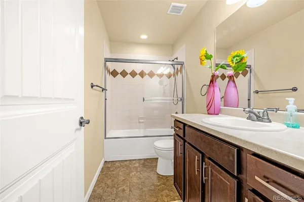 a bathroom with a granite countertop sink a toilet and shower