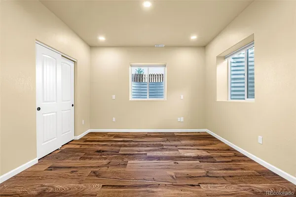 a view of an empty room with wooden floor and a window