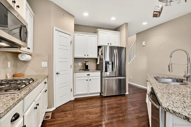 a kitchen with stainless steel appliances granite countertop a refrigerator and a stove top oven