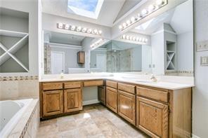 544 Lake Forest Drive Coppell, TX 75019 - Photo 20 of 24 a spacious bathroom with a granite countertop sink a mirror a bathtub and a shower