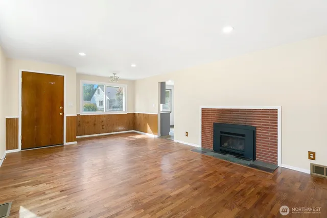 a view of empty room with wooden floor and fireplace