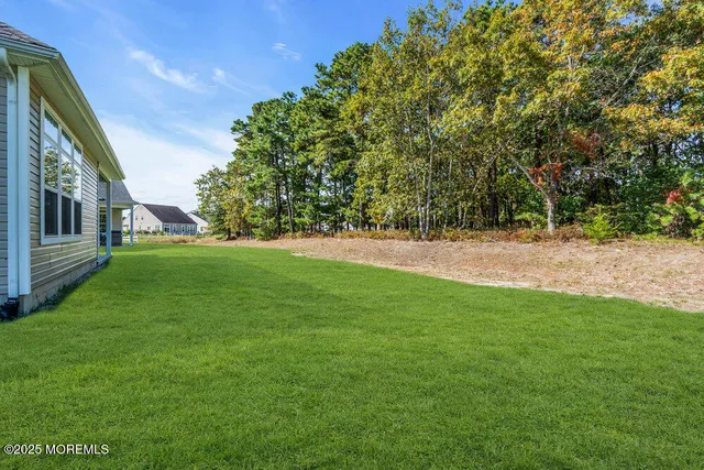 a view of a house next to a big yard and large trees