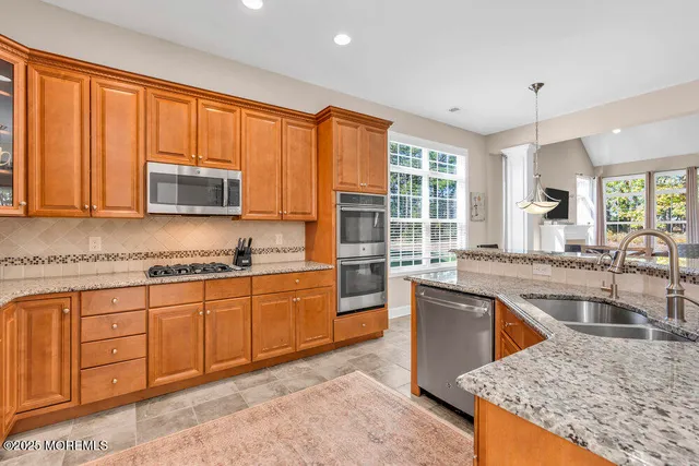 a kitchen with stainless steel appliances granite countertop a stove a sink dishwasher and a microwave oven with white cabinets