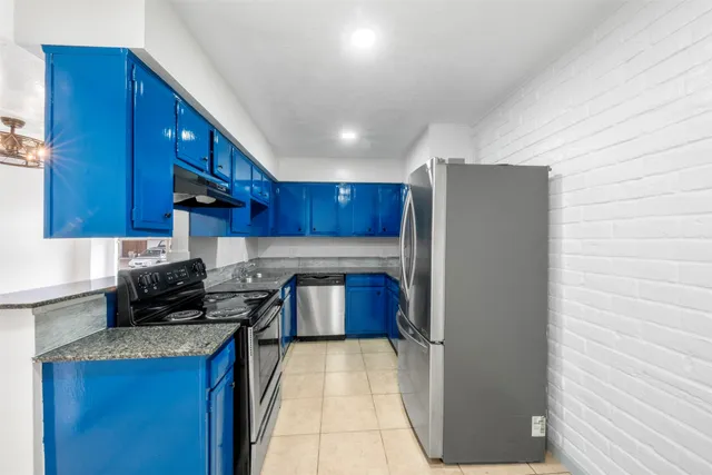 a kitchen with stainless steel appliances granite countertop a refrigerator a stove and a wooden cabinets