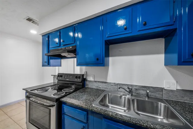 a kitchen with granite countertop a stove sink and cabinets