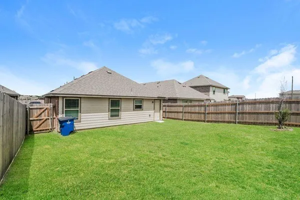 a view of a yard in front of a house with wooden fence