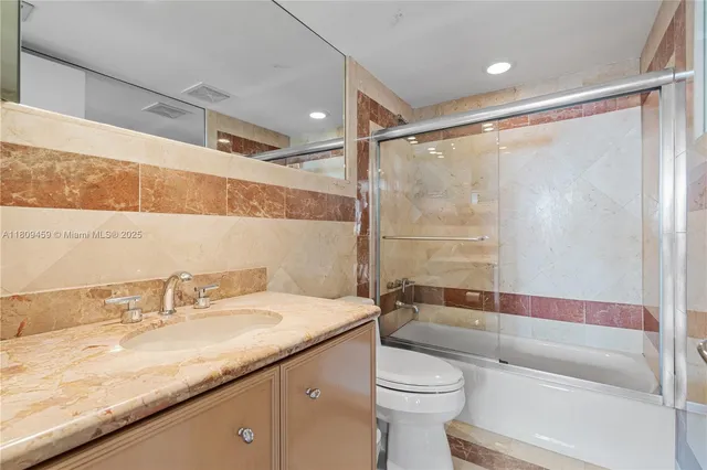 a bathroom with a granite countertop sink toilet and shower