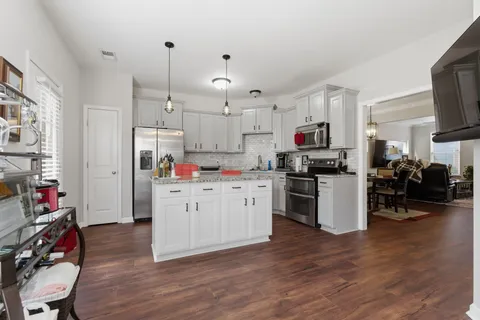 a kitchen that has a lot of white cabinets and wooden floor