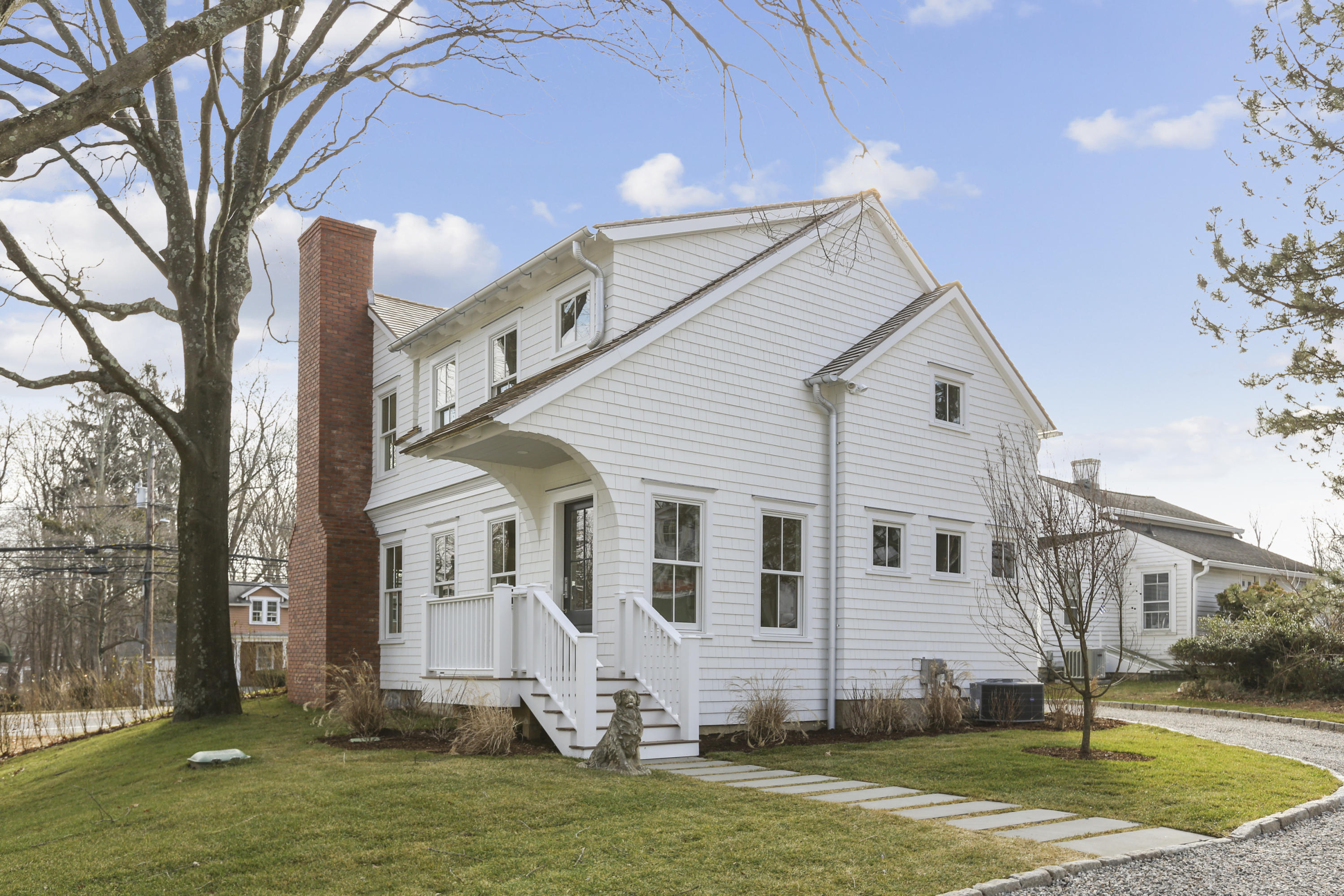 693 Post Road Darien, CT 06820 - Photo 24 of 41 a view of a white house next to a yard with big trees and plants