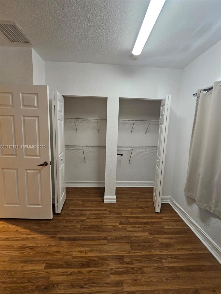 7995 Northwest 8th Street, Unit 103 Miami, FL 33126 - Photo 13 of 17 an empty room with wooden floor and closet area