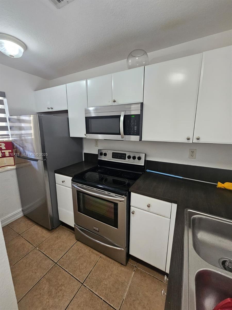7995 Northwest 8th Street, Unit 103 Miami, FL 33126 - Photo 3 of 17 a kitchen with granite countertop a stove and a refrigerator with cabinets