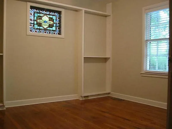 a view of an empty room with wooden floor and window