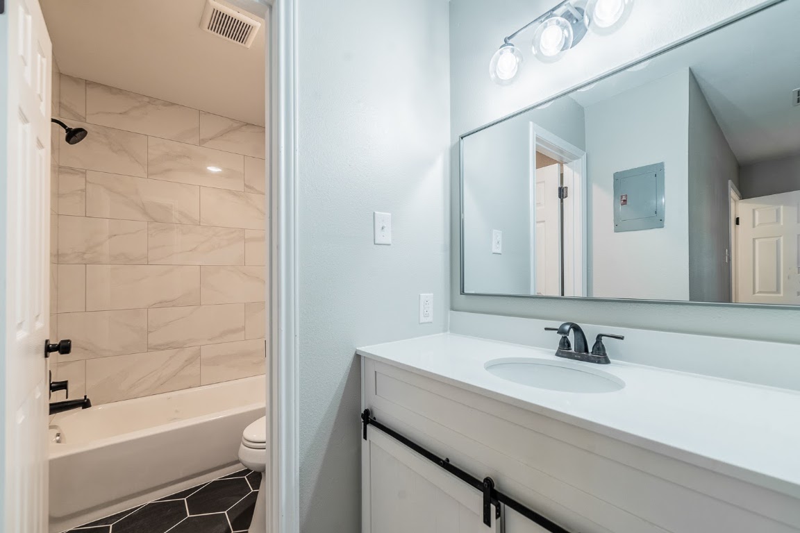 916 Sirocco Drive, Unit B Austin, TX 78745 - Photo 11 of 18 a bathroom with a granite countertop sink a toilet and shower