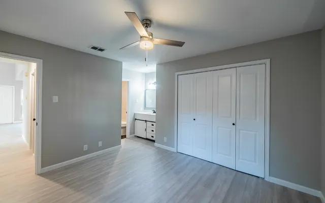 an empty room with wooden floor ceiling fan and windows