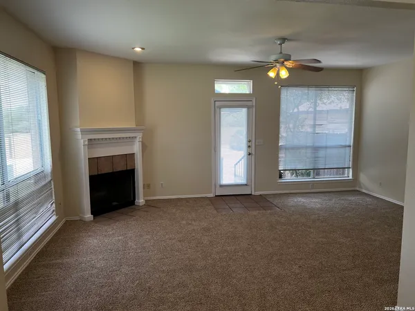 an empty room with windows and fireplace