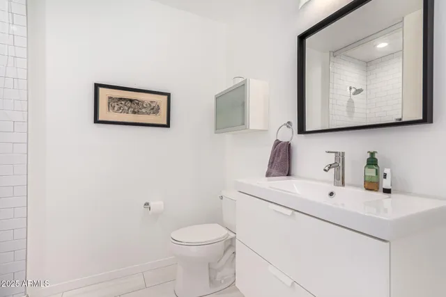 a bathroom with a toilet sink vanity and mirror