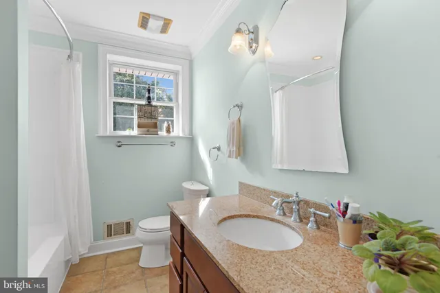 a bathroom with a granite countertop double vanity sink a mirror and a toilet