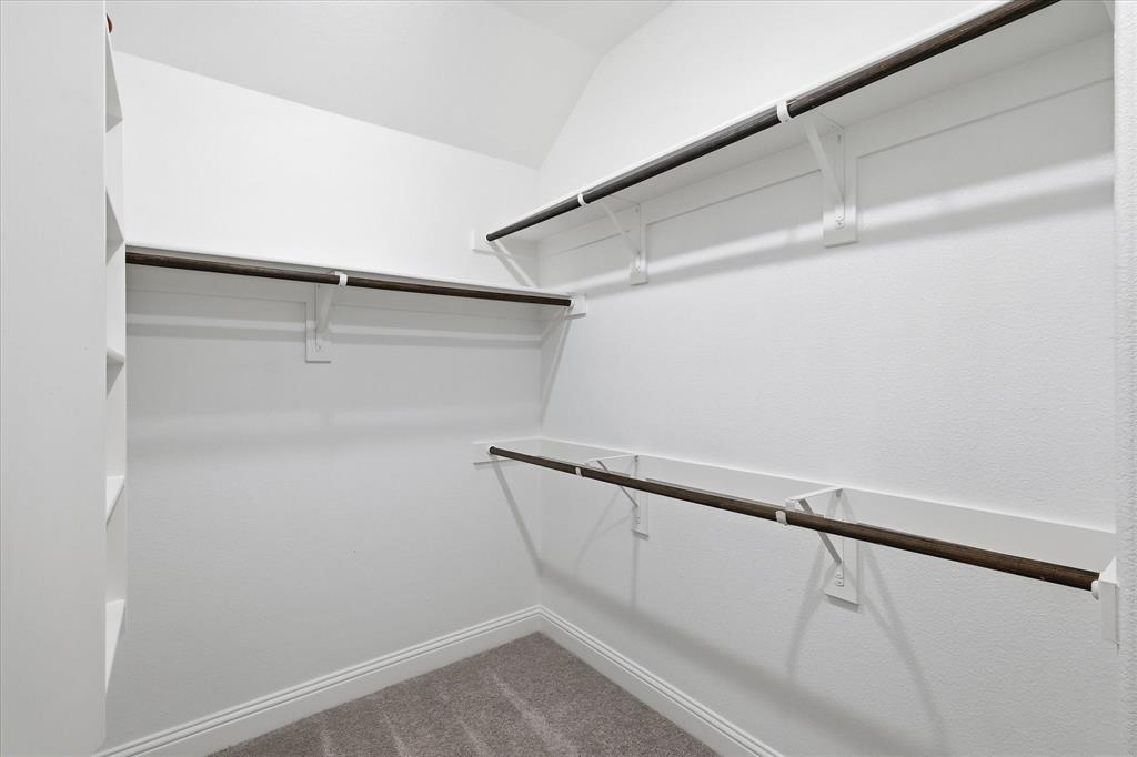 519 Sequoia Street Allen, TX 75002 - Photo 26 of 38 Walk-in closet featuring built-in shelving, multiple hanging rods, white walls, and a light-toned carpet