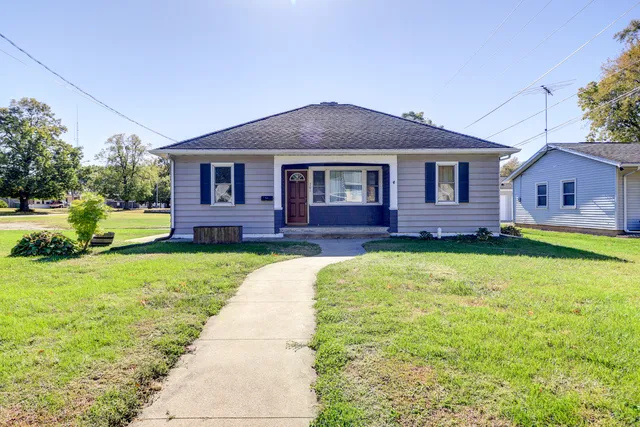 a brick house with a big yard plants and large trees