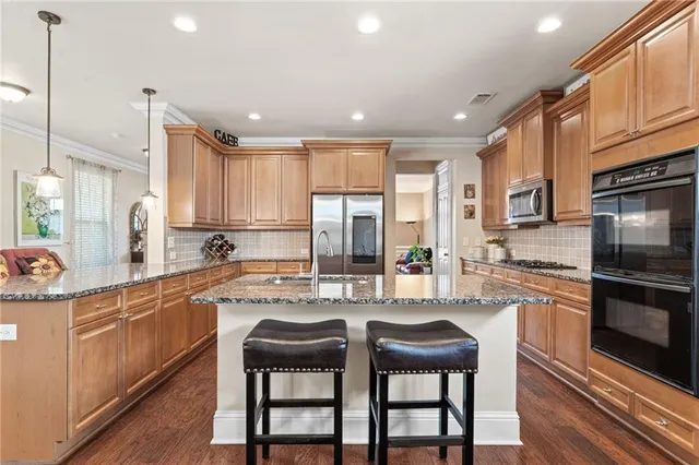 a kitchen with stainless steel appliances granite countertop a stove top oven a sink refrigerator and cabinets