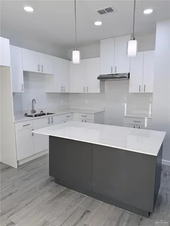 a kitchen with kitchen island a sink stainless steel appliances and cabinets