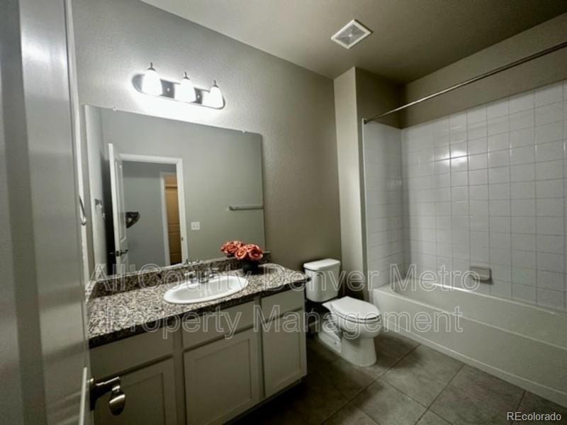 19580 West 92nd Drive, Unit E Arvada, CO 80007 - Photo 11 of 25 a bathroom with a granite countertop sink a toilet a mirror and shower