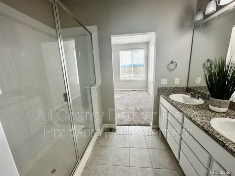 19580 West 92nd Drive, Unit E Arvada, CO 80007 - Photo 18 of 25 a bathroom with a granite countertop sink a mirror and a shower