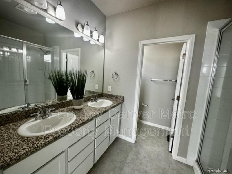 19580 West 92nd Drive, Unit E Arvada, CO 80007 - Photo 19 of 25 a bathroom with a granite countertop sink a mirror and a shower