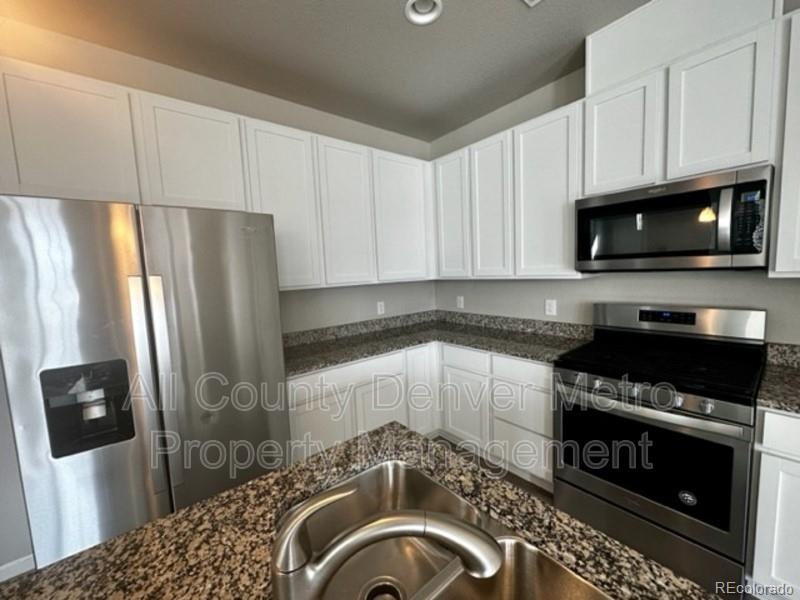 19580 West 92nd Drive, Unit E Arvada, CO 80007 - Photo 6 of 25 a kitchen with granite countertop a refrigerator stove and microwave