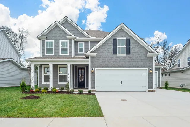 a view of a white house with a small yard and large tree